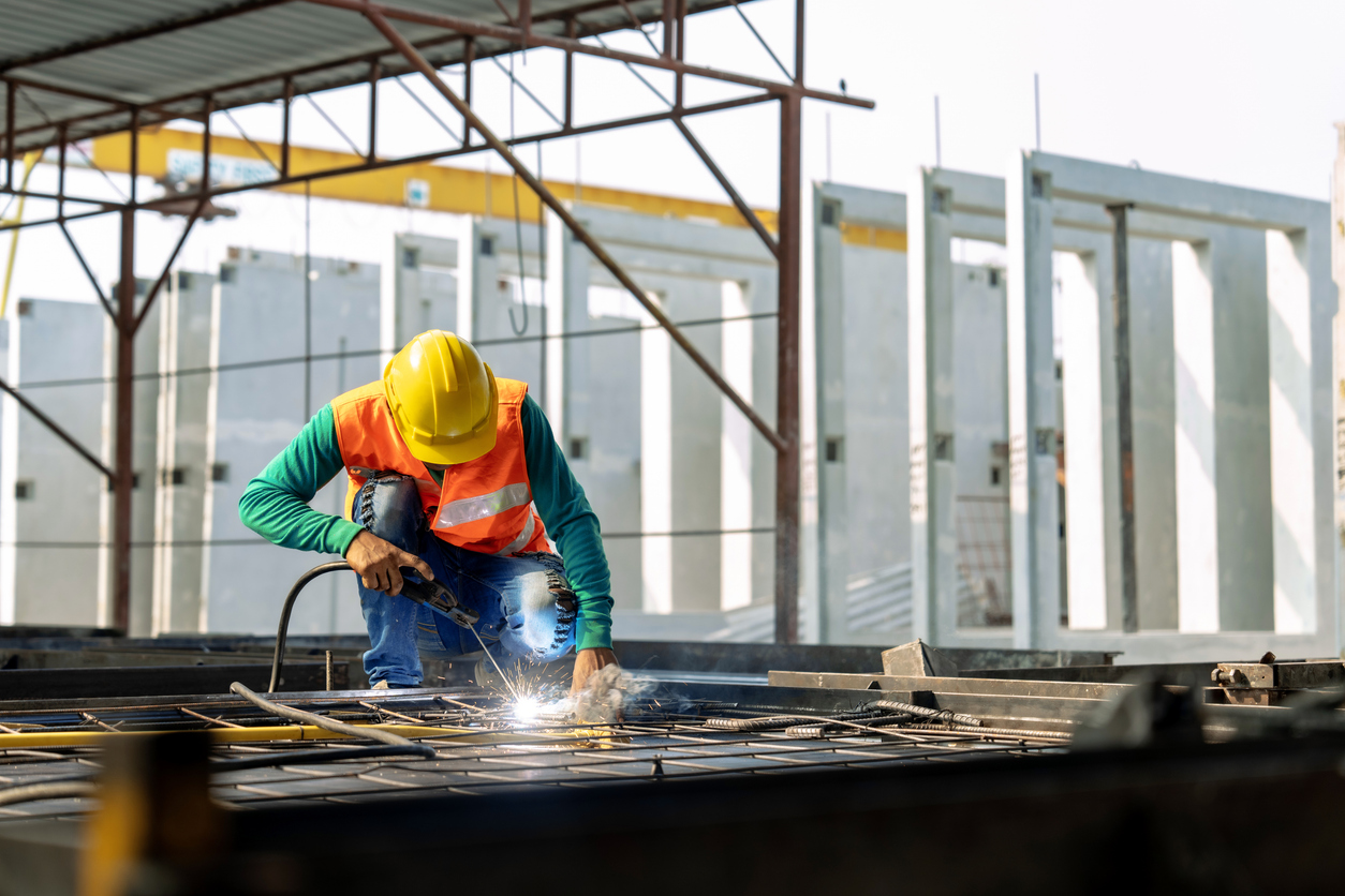 Worker at an infastructure manufacturing site welding cnc machined construction components.